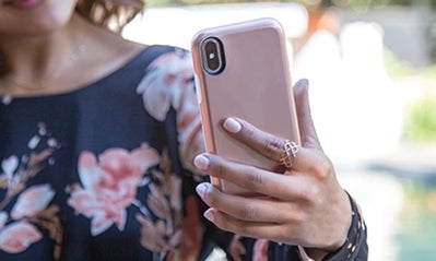 women in floral shirt holding a phone with a pink case